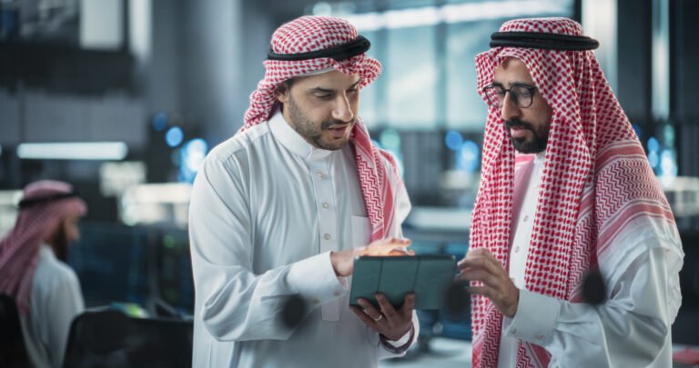 Two Young Muslim Software Engineers Use Tablet Computer to Discuss a Technological Project in a Modern Industrial Office
